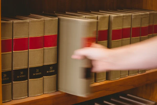 Hand nimmt ein Buch aus dem Bücherregal — Stockfoto