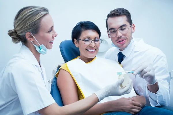 Dentist with assistant showing woman — Stock Photo, Image