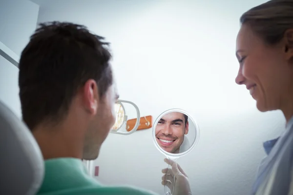 Sorridente giovane uomo guardando lo specchio — Foto Stock