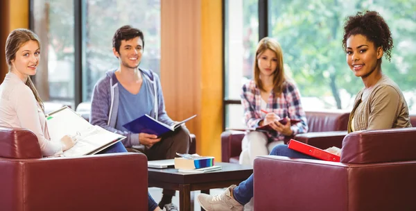 Les étudiants assis sur le canapé révisant et souriant à la caméra — Photo