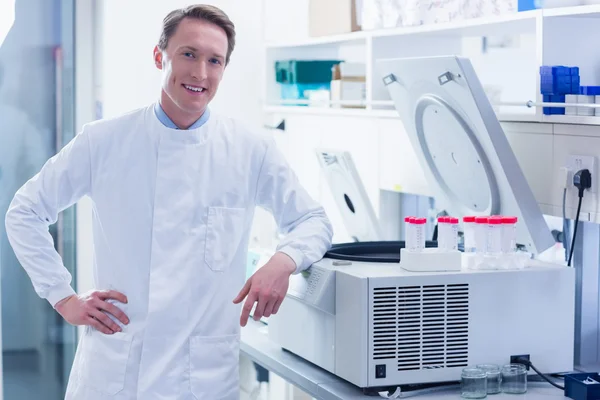 Lachende scheikundige leunend tegen de centrifuge — Stockfoto