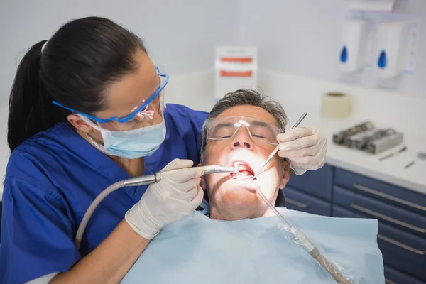 Dentista examinando um paciente com ferramentas e luz — Fotografia de Stock