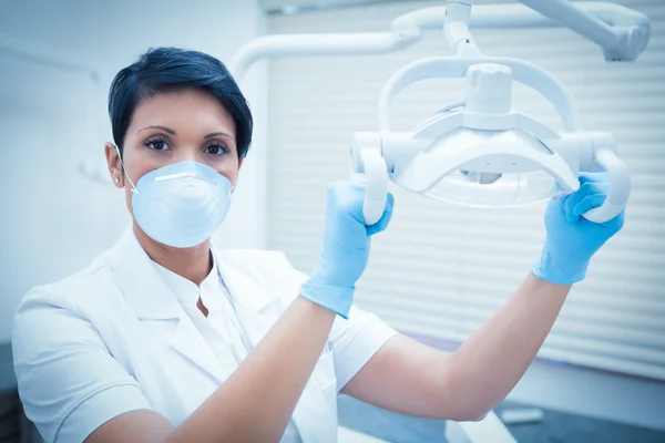 Demale tandarts in chirurgische masker licht aanpassen — Stockfoto