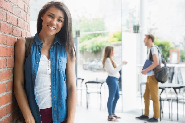 Bella studentessa sorridente alla macchina fotografica con i compagni di classe dietro — Foto Stock