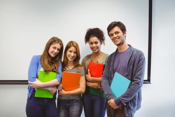 Students standing and smiling at camera holding notepads — Stock Photo, Image