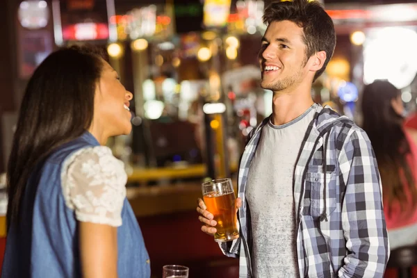 Lächelnde Freunde, die miteinander reden und Bier und Mixgetränk trinken — Stockfoto
