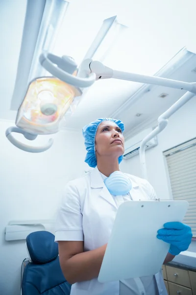 Dentist with clipboard looking up — Stock Photo, Image