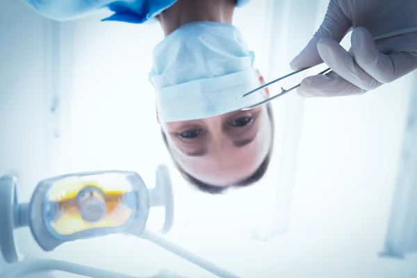 Dentista femenina en máscara quirúrgica sosteniendo herramienta dental —  Fotos de Stock