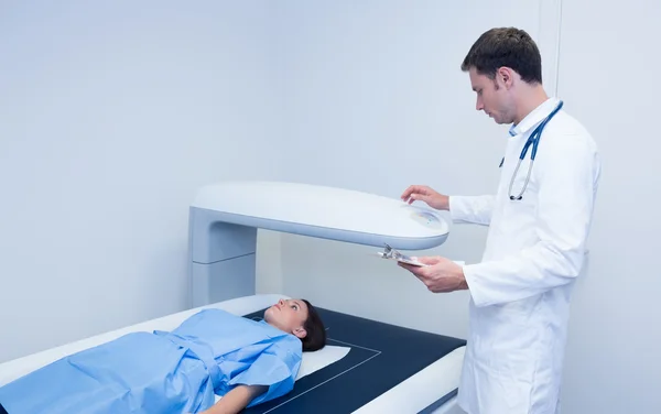 Doctor holding a radiography machine over a patient — Stock Photo, Image