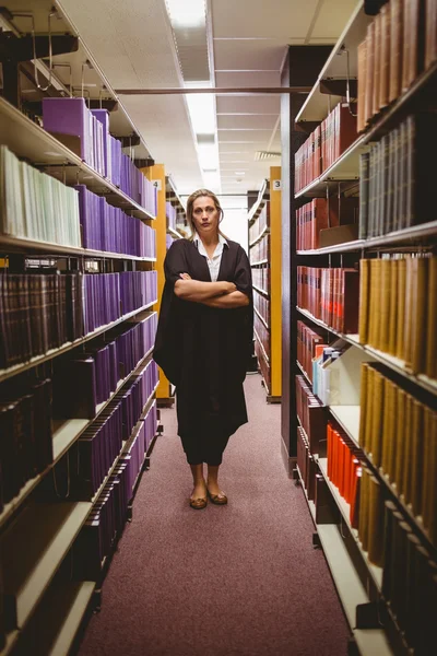 Stern lawyer standing between shelfs with arms crossed — Stock Photo, Image