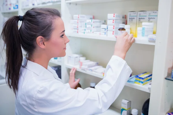 Smiling student taking jar from shelf — Stock Photo, Image