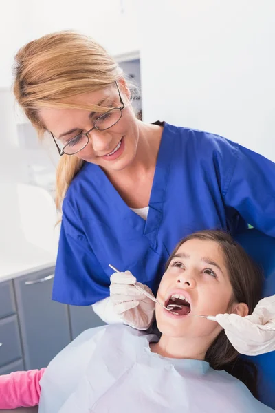 Dentista haciendo examen a un paciente joven asustado — Foto de Stock