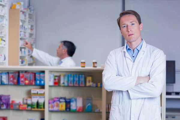 Unsmiling pharmacist standing with arms crossed — Stock Photo, Image