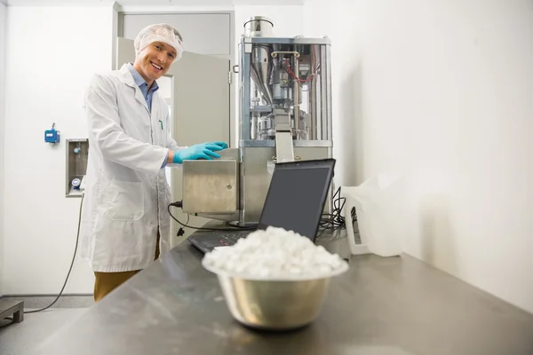 Farmacêutico que utiliza máquinas para fabricar medicamentos — Fotografia de Stock