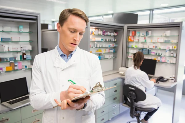 Focused pharmacist writing on clipboard — Stock Photo, Image