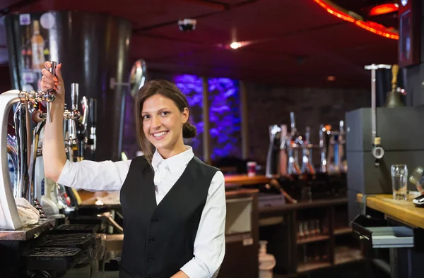 Happy barmaid pulling a pint of beer — Stock Photo, Image