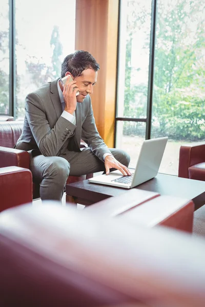 Homem feliz falando ao telefone com seu laptop — Fotografia de Stock