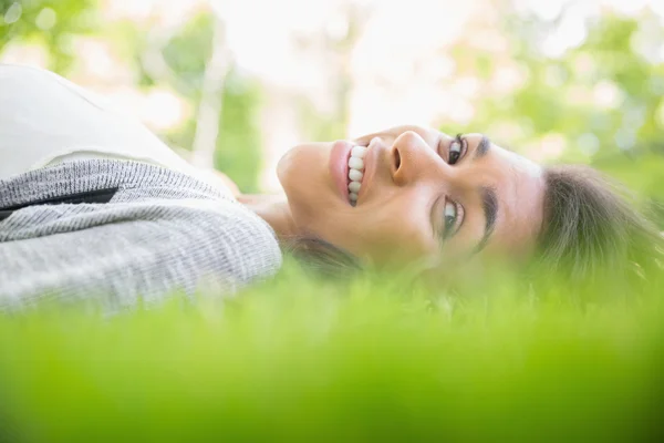 Hezká brunetka ležící na trávě — Stock fotografie