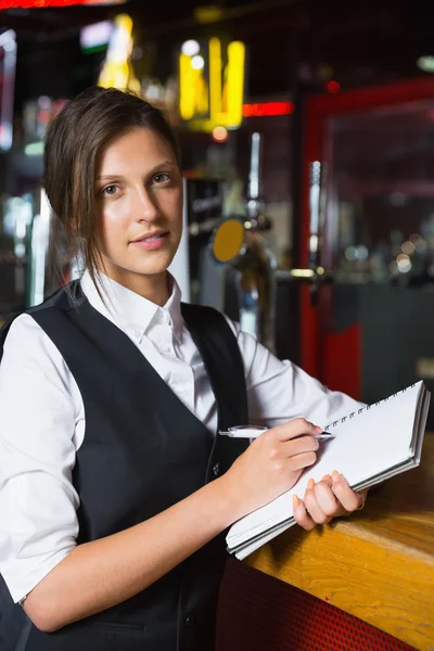 Fröhliche Bardame schreibt in Notizblock — Stockfoto