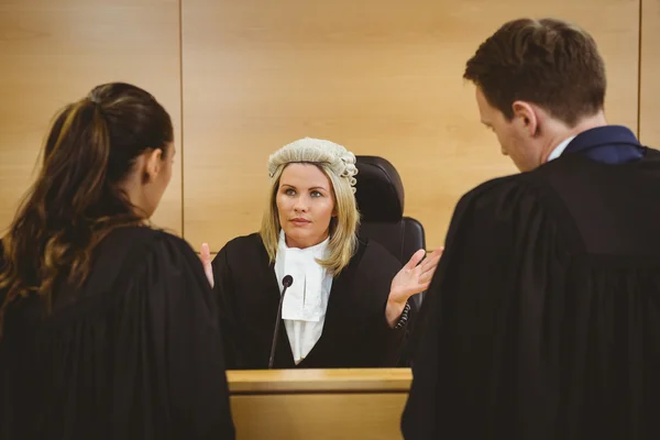 Judge wearing a dress and a wig speaking with lawyers — Stock Photo, Image