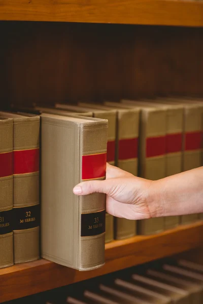 Hand taking a book from bookshelf — Stock Photo, Image