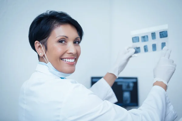 Dentista sonriente sosteniendo rayos X — Foto de Stock