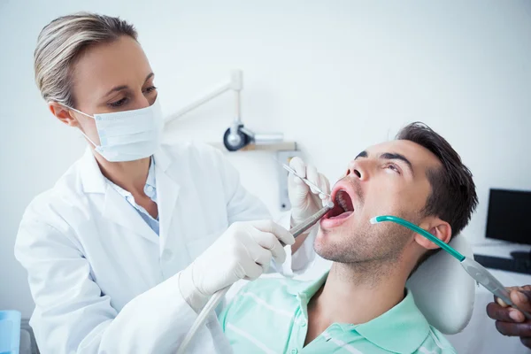 Dentista femminile esaminando denti mans — Foto Stock