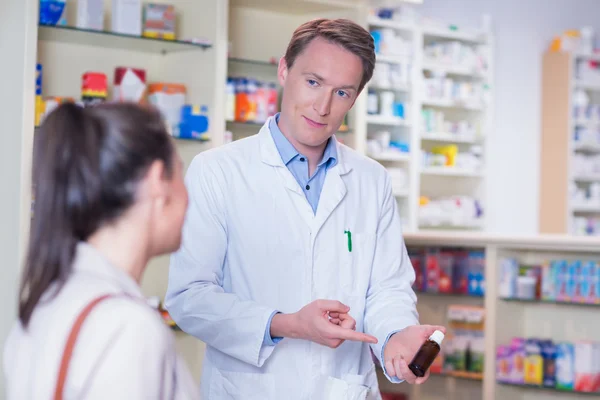 Фармацевт указывает на фляжку с таблетками — стоковое фото