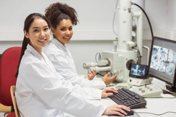 Science students working with microscopic image on computer — Stock Photo, Image