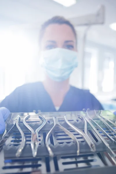 Dentista in camice blu che mostra vassoio di strumenti — Foto Stock