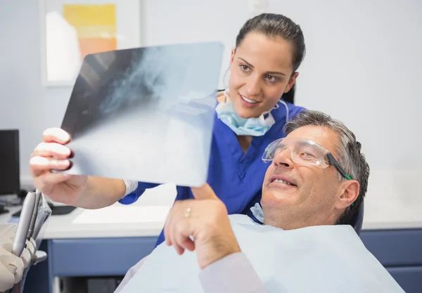 Dentista sonriente mostrando radiografía a su paciente — Foto de Stock