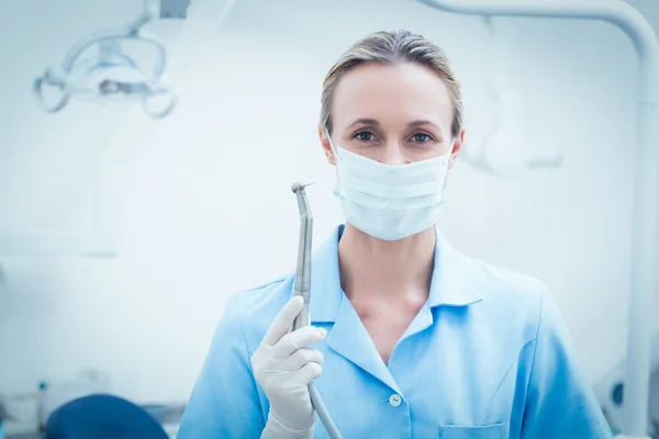 Dentista feminina em máscara cirúrgica segurando ferramenta dentária — Fotografia de Stock