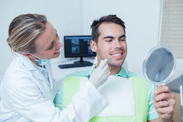 Dentista femminile esaminando denti mans — Foto Stock