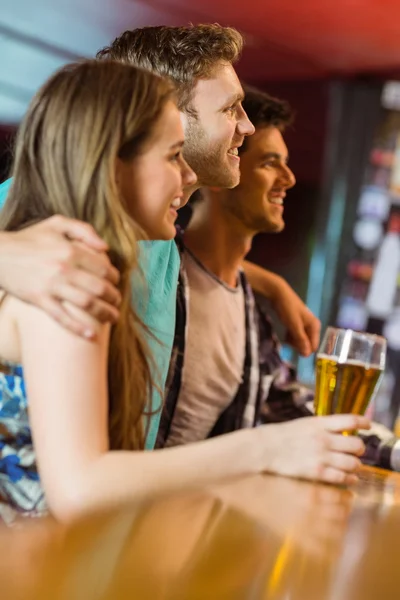 Sorridente capelli castani in piedi con il braccio intorno ai suoi amici — Foto Stock