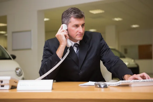 Gerichte zakenman met behulp van laptop op de telefoon — Stockfoto