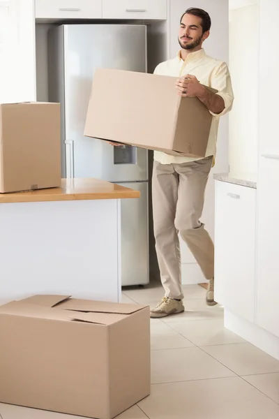 Young man unpacking boxes in kitchen — Stock Photo, Image