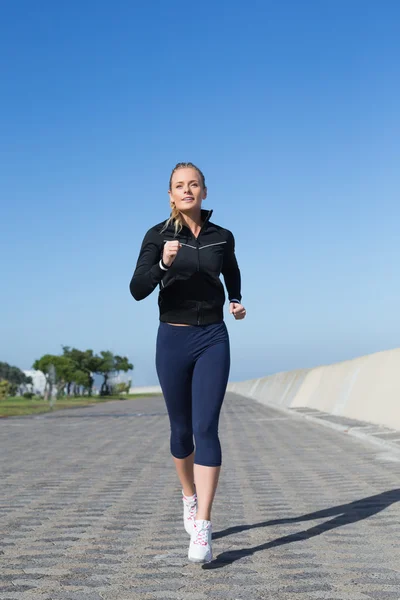 Fit blonde joggen op de pier — Stockfoto