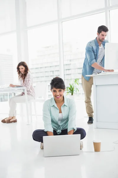 坐在地板使用的便携式计算机上的女商人 — 图库照片
