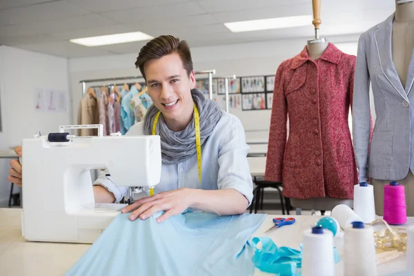 Улыбающийся студент с помощью швейной машинки — стоковое фото