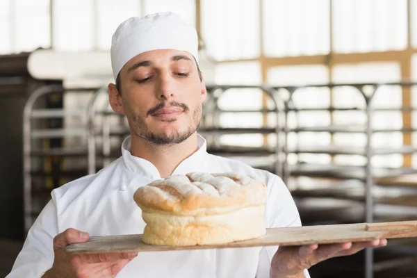 Baker smelling a freshly baked loaf — Stock Photo, Image