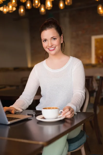 Brunette having coffee using laptop — Stock Photo, Image