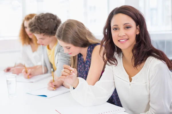 Fashion students smiling at camera in class — Stock Photo, Image