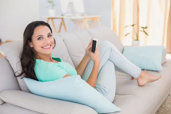 Brunette sending text on couch — Stock Photo, Image