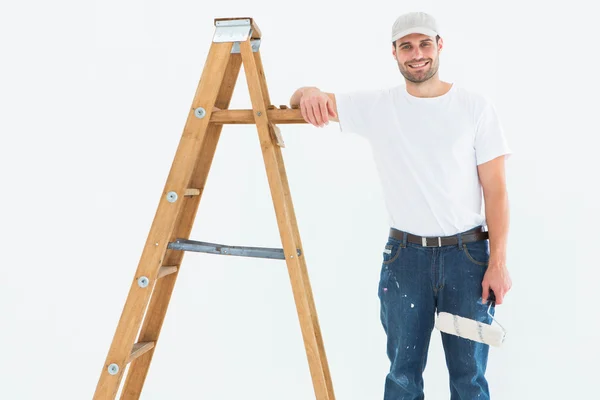 Glücklicher Mann mit Farbwalze auf Leiter — Stockfoto