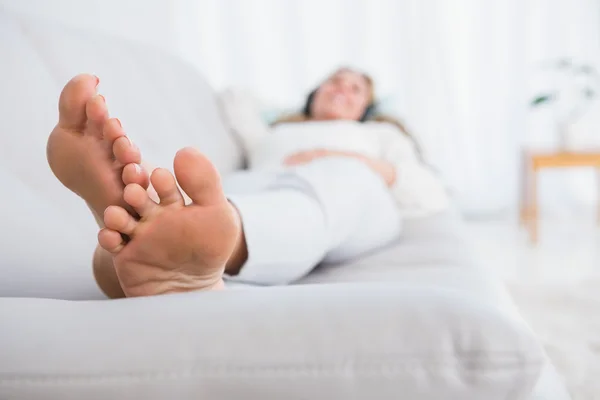 Blonde lying on couch listening music — Stock Photo, Image