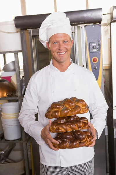 Smiling baker holding fresh loaves — Stock Photo, Image