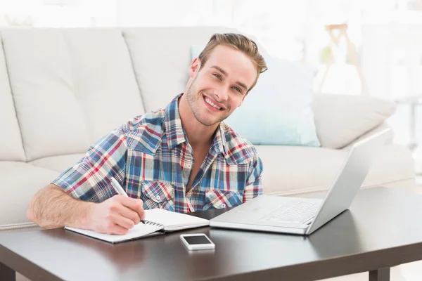 Smiling man writing on a notebook — Stock Photo, Image