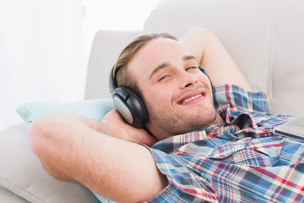 Hombre acostado en el sofá escuchando música — Foto de Stock