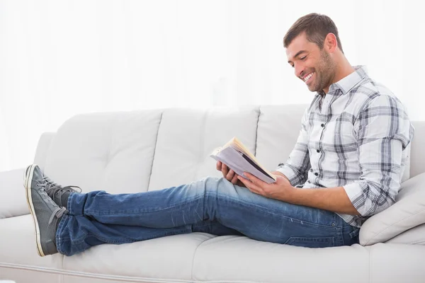 Relaxante homem em um sofá com um livro — Fotografia de Stock