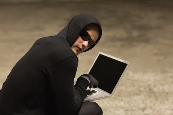 Hacker in maglione incappucciato con computer portatile — Foto Stock